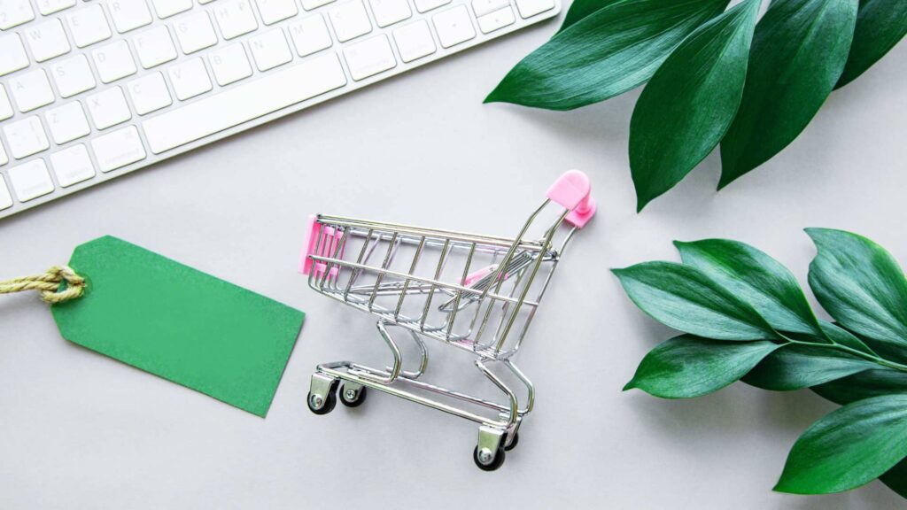 Miniaturowy koszyk zakupowy na biurku leżacy obok latopa symbolizujący zakupy z dotacji z urzędu pracy